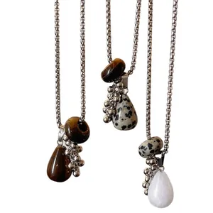 Macro view of teardrop tiger eye stone pendants on silver beaded chains