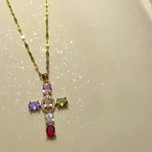 Gros plan du collier croix doré avec pierres de zircone multicolores pour femmes