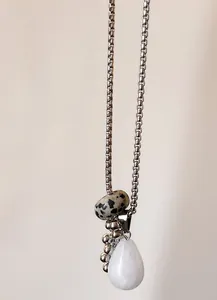 Detail of teardrop stone pendant with Dalmatian Jasper bead on long square link chain