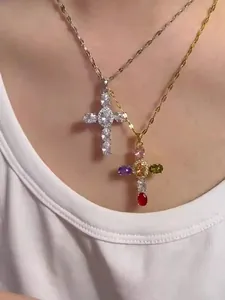 Détail de colliers avec pendentif croix et zircons colorés portés par un mannequin en or et argent