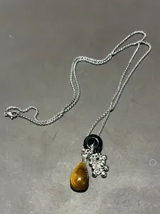 Detail of tiger eye teardrop pendant with black ring and silver beaded cluster necklace