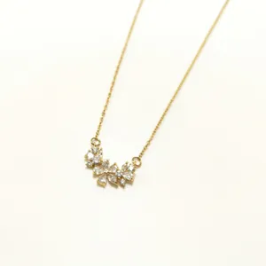 Gold chain necklace with three sparkling rhinestone flower pendants on a cream background