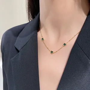 Detail van 18K vergulde titanium ketting met drie vierkante groene zirkonia hangers