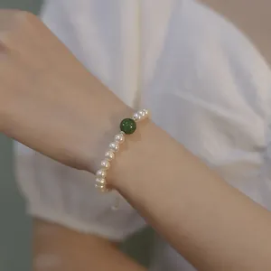 Elegante parelarmband met groene kattenoogsteen en gouden accenten om een pols