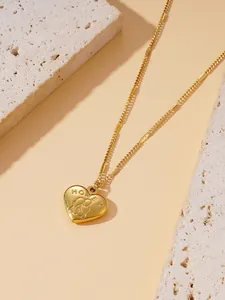 Gros plan d'un pendentif cœur doré avec gravure Honey et silhouette d'ours mignonne