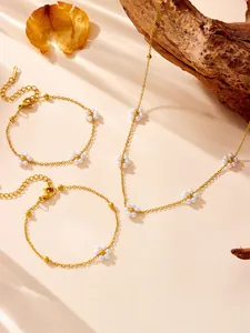 Detail of gold chain necklace and bracelet set featuring delicate pearl flower charms