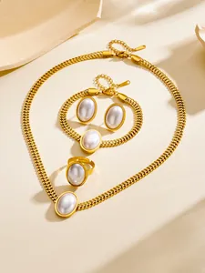 Detailed view of chunky gold chain jewelry set with large white oval pearls on beige stone