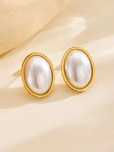 Close-up of vintage oval pearl earrings with elegant gold metal frames on warm background
