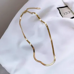 Elegante collar de cadena de serpiente dorada con cierre ajustable sobre tela blanca suave
