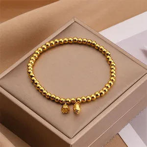 Primer plano de pulsera dorada con dijes de loto y semilla sobre una caja de joyería