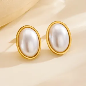 Elegant gold-tone oval stud earrings with white pearl inlay set on a soft beige background