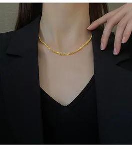 Close-up of sparkling gold titanium steel chain necklace worn by a model in a black suit