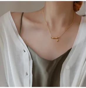 Detailed close-up of a gold bamboo pendant necklace worn on a woman's collarbone