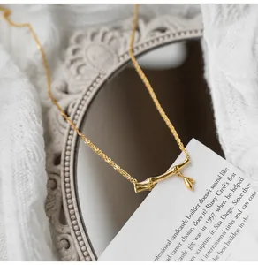 Detail of golden bamboo pendant and leaf on a fine chain with minimalist aesthetic