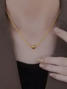 Detail shot of a minimalist gold beaded pendant necklace on a model's neck