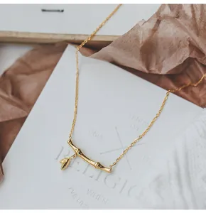 Detail of gold bamboo pendant with leaf charm on O-chain necklace in minimalist style