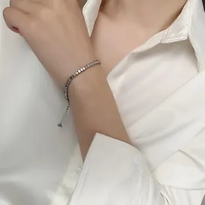 Detail of minimalist silver beaded bracelet with adjustable chain on model's wrist