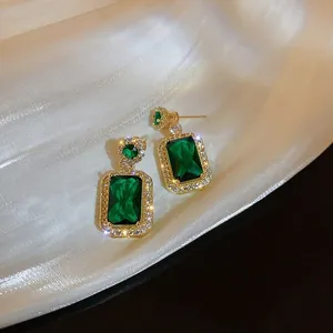 Detail of emerald cut green crystal earrings with gold plating and pavé setting