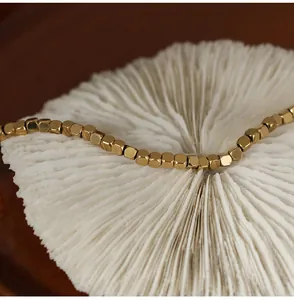 Macro view of 18K gold plated beaded bracelet with faceted metallic cube texture