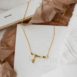 Titanium steel gold bamboo necklace with a delicate leaf pendant on a white backdrop