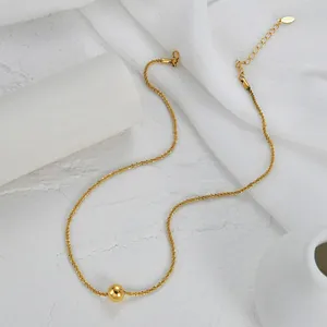 Close-up of golden sphere pendant on shimmering sand-textured chain with lobster clasp