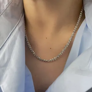 Gros plan d'un collier à maillons argentés porté sur une chemise bleu clair