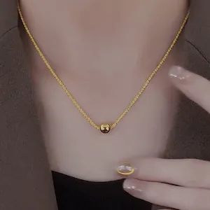 Elegant gold titanium ball pendant necklace with woven chain worn on a stylish model