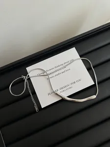 Nahaufnahme der minimalistischen Titanstahl-Schlangenkette mit gebogenem Metallanhänger