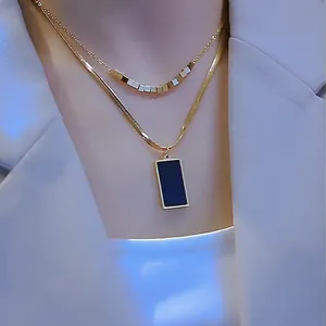 Collar de doble capa dorado con colgante cuadrado negro mostrado en modelo real