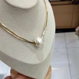 Detail of double-layer gold snake chain featuring a large white pearl on a display stand