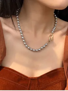 Détail macro d'un collier à perles argentées avec fermoir doré sur modèle