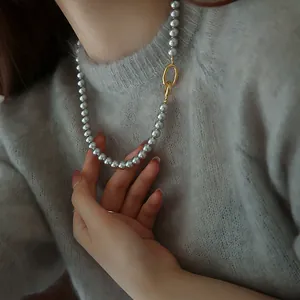 Collier de perles gris argenté avec fermoir doré asymétrique sur pull en laine