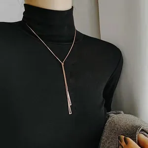 Rose gold geometric Y-shaped necklace with bar pendants on a black turtleneck sweater