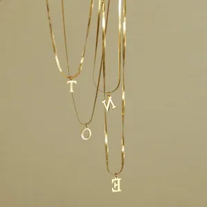 Dettaglio di quattro catene a serpente dorate con pendenti a forma di lettere T, O, V e E