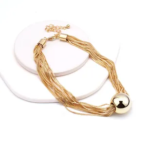 Dettaglio della collana a catena multipla dorata con grande pendente a sfera lucida
