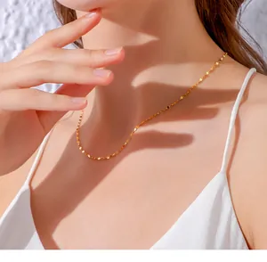 Close-up of a gold-plated stainless steel flat cable chain necklace on a model