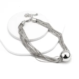 Dettaglio di una collana a più strati argentata con un pendente sferico lucido
