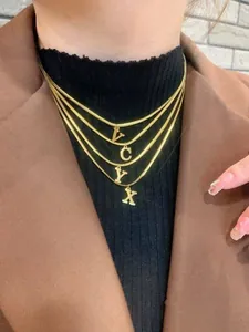 Dettaglio della collana a quattro strati in maglia serpente dorata con ciondoli lettere