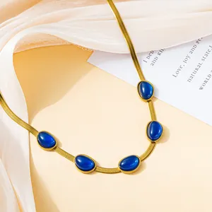 Detailed view of a gold blade chain necklace with five smooth oval blue gemstones