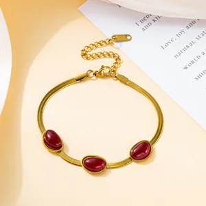 Close-up of golden blade chain necklace featuring three oval red emerald gemstones