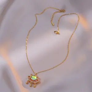 Golden Ruyi lock necklace with green gemstone and small beads on grey silk fabric
