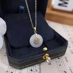 Collier en or élégant avec pendentif en jade blanc et caractère Fu sur fond de partition