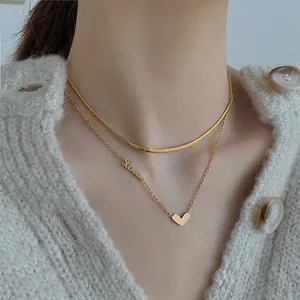 Nahaufnahme der zweilagigen goldenen Herzkette mit Love-Anhänger auf weißem Pullover