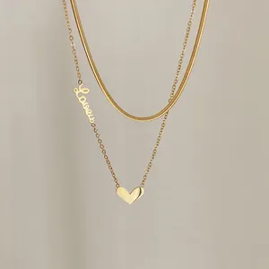 Nahaufnahme der goldenen zweilagigen Kette mit Love-Schriftzug und Herz-Anhänger-Detail
