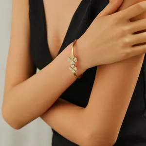 Bracelet trèfle doré avec zircons brillants porté par un mannequin au poignet