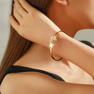 Bracelet trèfle élégant plaqué or serti de zircons porté au poignet pour un style raffiné