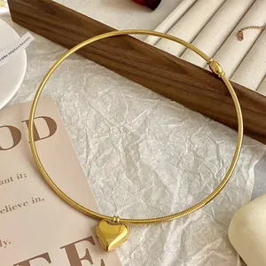 Detailansicht einer goldenen Herzanhänger-Halskette auf einem Holztablett bei warmem Licht