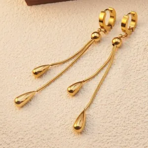 Close-up of golden tassel drop earrings featuring snake chains and waterdrop pendants