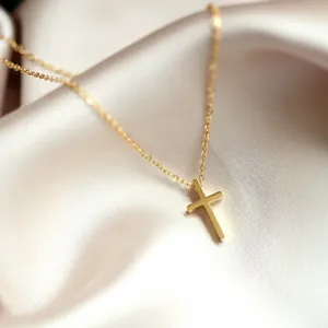 Gros plan d'un pendentif croix dorée minimaliste sur un tissu en satin blanc