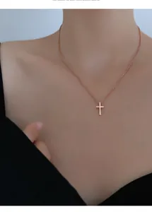 Gros plan d'un collier croix minimaliste en or rose porté pour un style élégant